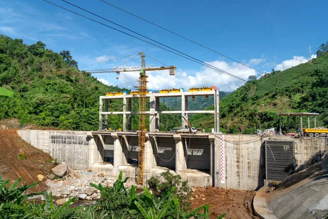 Crane operating at a construction site in a lush, mountainous area under bright blue skies. Droit de recours des associations : projets sectoriels, conditions, procédure